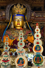 Monks stand before a Golden Buddha statue in Pelkor Chode Monastery in Tibet.