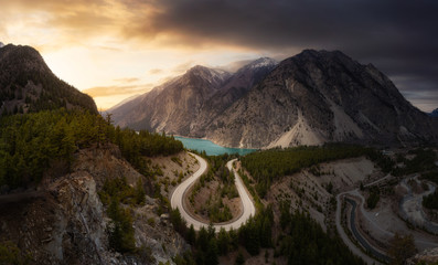 Aerial View of a Scenic Road in the Canadian Mountain Landscape during a cloudy sunset. Sky...