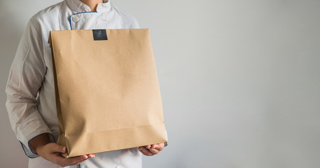 Chef making a delivery of food takeaway in a paper carton bag with copy space