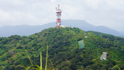   large color radio antenna on top of the mountain. satellite dish on top of green mountain panorama