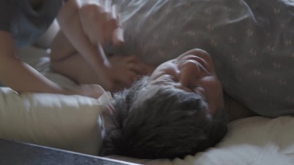 little boy wake up their dad.  Cute toddler son and father sleeping together on bed in bedroom at home.