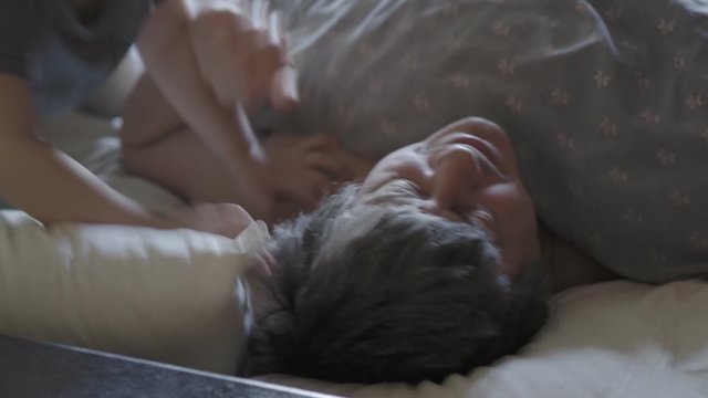 little boy wake up their dad.  Cute toddler son and father sleeping together on bed in bedroom at home.