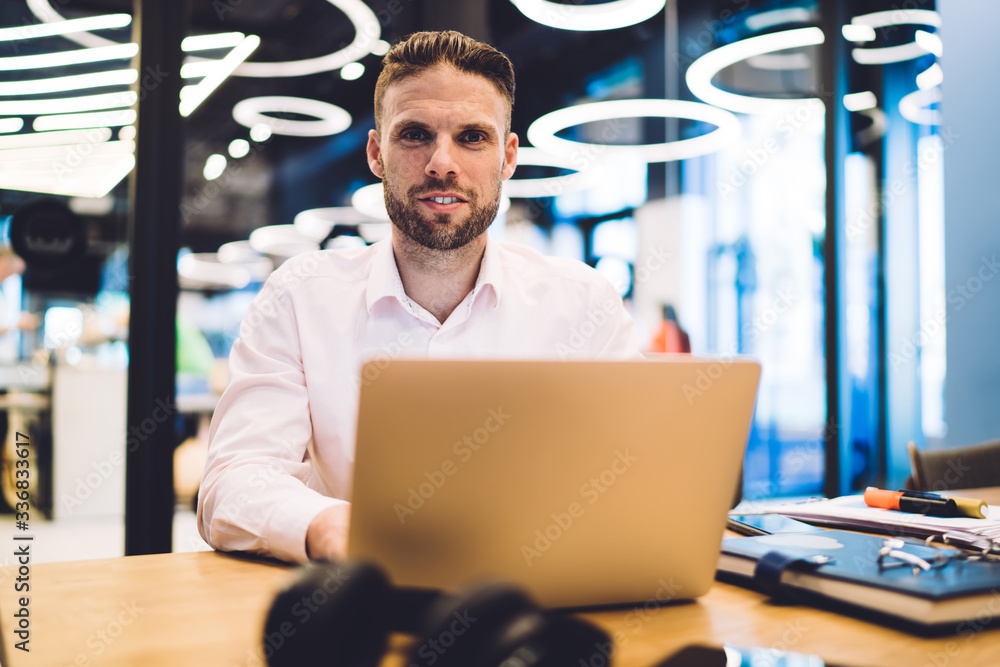 Poster portrait of caucasian male it developer 30s installing app on laptop computer sitting at table deskt