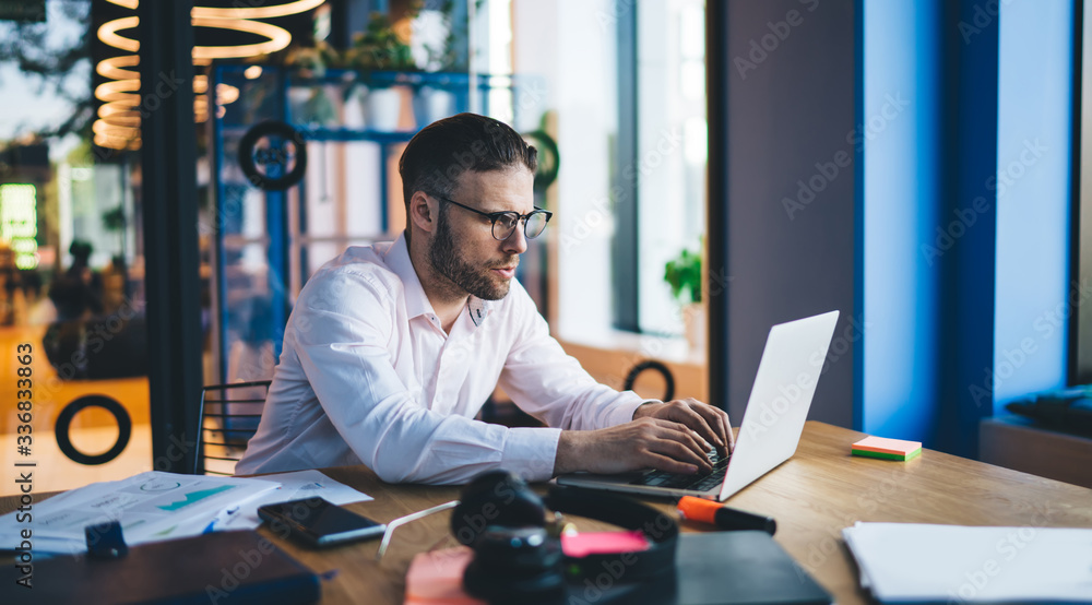 Poster caucasian male software developer sitting at coworking desktop with laptop technology and creating p