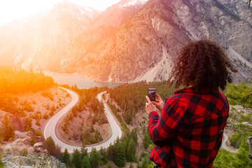 Adventurous Girl Taking Pictures of a Scenic Road in the Canadian Mountain Landscape during a sunny evening. Taken between Pemberton and Lillooet, BC, Canada.