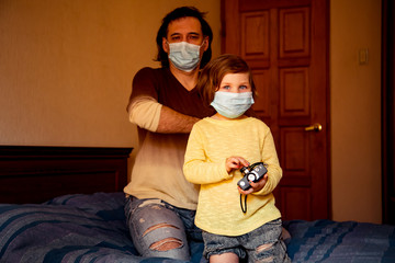 daddy and daughter in medical masks, studying art photography, at home during quarantine, due to...