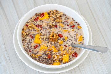 Granola with yellow mango, red goji berries and almond milk, closeup
