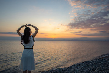 Fototapeta premium 夕日の浜辺を歩く女性