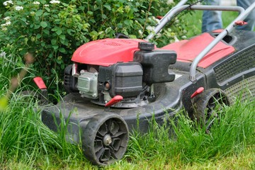 Working lawn mower on green lawn with trimmed grass