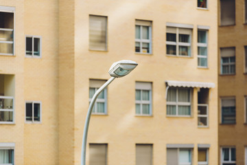Daytime public streetlight focus behind unfocused residential buildings.