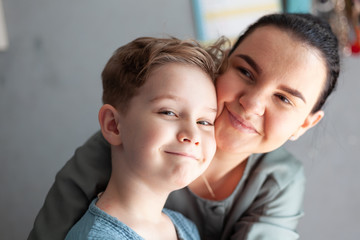 Child with autism and down syndrome smiles happily in the arms of a happy mother Dual Diagnosis