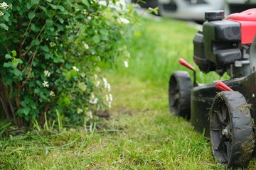 Working lawn mower on green lawn with trimmed grass