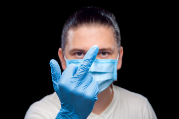 hand in glove showing obscene gesture middle finger male portrait of a doctor in a medical mask, closeup isolated on black background.