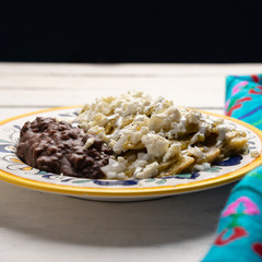 Mexican green chilaquiles with beans on white background