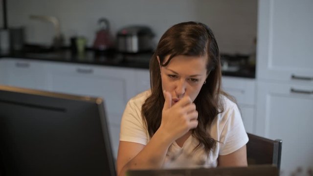 A young, beautiful woman is looking at a computer monitor. Remote work. Online teaching. The teacher shows the exercise. The neuropsychologist works remotely. Home furnishings.