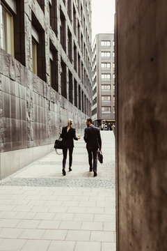 Rear view of business people talking while walking by building in city