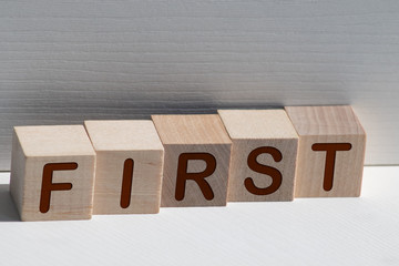 Word FIRST is written on wooden blocks on a light background.