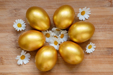 Obraz na płótnie Canvas Ester golden eggs and daisies on wooden rustic table.