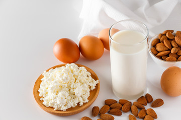 High protein food on a white background - cottage cheese, eggs, nuts. A set of healthy foods for a balanced diet.