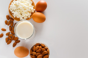 Rustic homemade protein balanced diet food. Cottage cheese, eggs, nuts and milk on a white background.