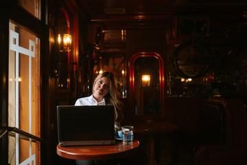 Obraz na płótnie Canvas Attractive young caucasian blonde businesswoman working on laptop in cafe