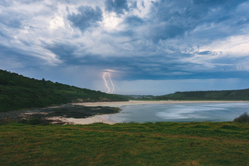 beach scenery as lightning strikes the sea in australia whit clouds