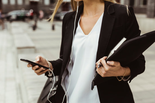 Midsection of female entrepreneur with mobile phone standing on sidewalk