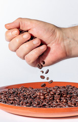 hand spilling coffee beans on a clay plate