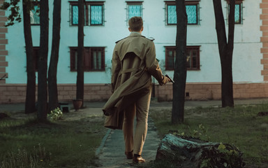 Film noir Detective man in a raincoat in a dangerous with a gun in his hand