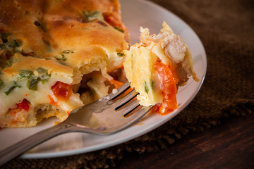 Delicious homemade pie with chicken, herbs and tomatoes on a plate.