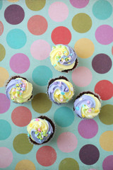 Fototapeta na wymiar Three yellow and purple easter cupcake on lined background