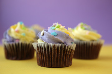 Top view of yellow and purple easter cupcake on lined background