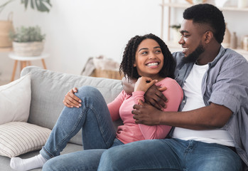 Romantic black couple relaxing at home, embracing and enjoying isolation together