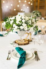 banquet table is decorated with plates, cutlery, glasses, candles and flower arrangements