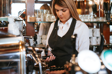 A young attractive blonde caucasian  waitress pouring beer in a cafe