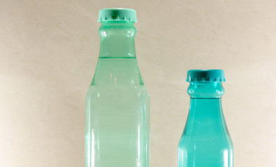Colored glass bottles with natural water on light and illuminated background