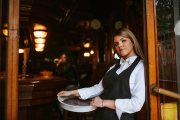 A young attractive caucasian blonde waitress with a tray in a cafe