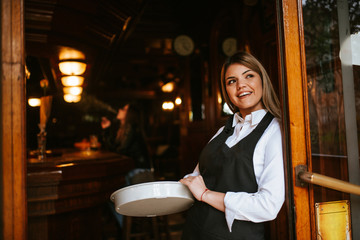 A young attractive caucasian blonde waitress with a tray in a cafe