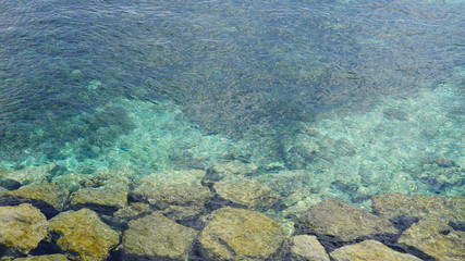 rocky shore. big green stones in turquoise blue water of the ocean. clear  sea water off the coast of a tropical island