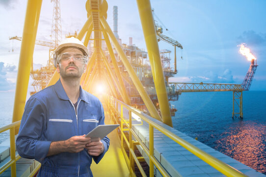 Caucasian man engineer staff worker with tablet in hand and offshore rig background concept.