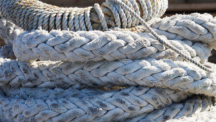 Fototapeta na wymiar Large ship ropes folded to dry on the shore. mooring bays stacked by a bay on a sunny day