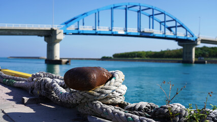 Fototapeta premium berth in the passenger port. Mooring points of the ship are fixed in the port. bright rusty bollard with ship ropes. against the background of a passenger ship and a bridge
