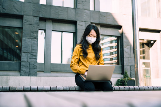 Businesswoman with face mask working using laptop
