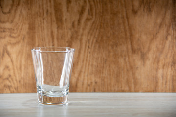 Glass cups on clear surface and woody background