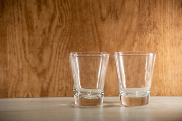 Glass cups on clear surface and woody background