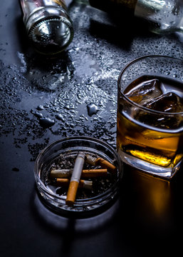 High Angle View Of Whiskey Glass And Cigarettes In Ashtray On Table