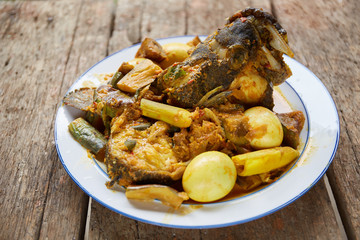 Tasty fish curry cooked in coconut milk on wooden table