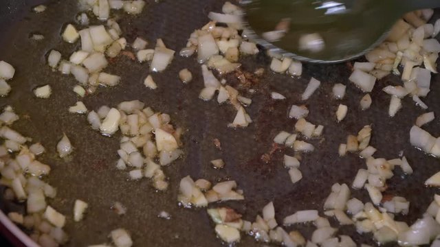 Fresh sliced onions sauteing in frying pan on stove top oven. Caramelized white onions cooking in silver saute pan.