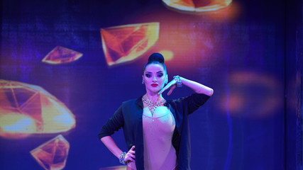 beautiful brunette posing in front of the camera on stage. girl ballroom dancer in the spotlight,...