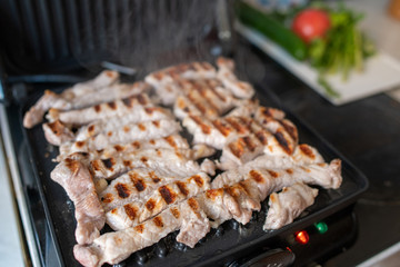 Cooking beef and pork meat on an electric grill at home